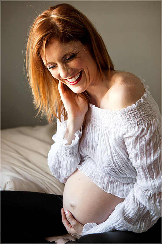 red-head laughing with pregnant belly